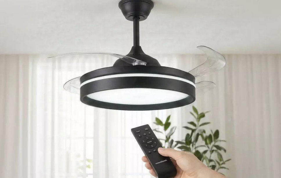 Las aspas de este ventilador de techo se esconden cuando lo apagas Imagen que muestra el ventilador de techo con las aspas abiertas y una mano cambiando la luz con el mando