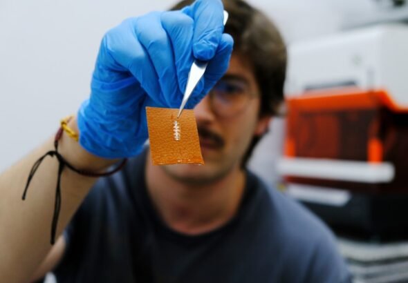 Imagen del investigador investigador Yigit Sozen que sostiene una papel de "calcomanía" con el chip integrado.