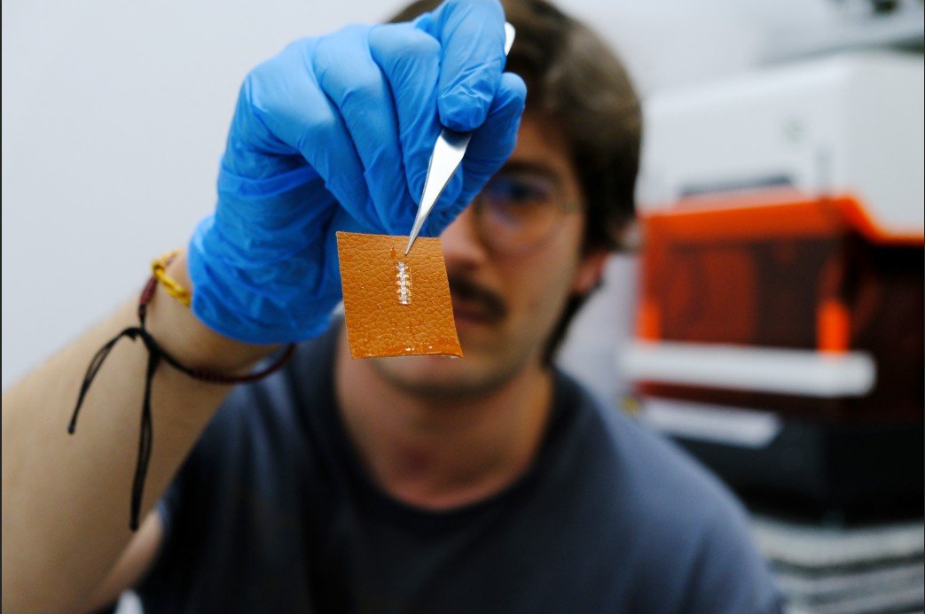 Imagen del investigador investigador Yigit Sozen que sostiene una papel de "calcomanía" con el chip integrado.