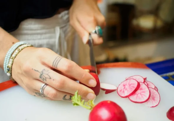 Imagen que muestra a una persona que ha obtenido el curso de manipulador de alimentos cortando verduras