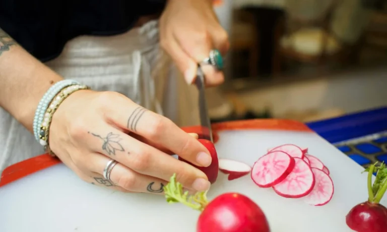 Imagen que muestra a una persona que ha obtenido el curso de manipulador de alimentos cortando verduras