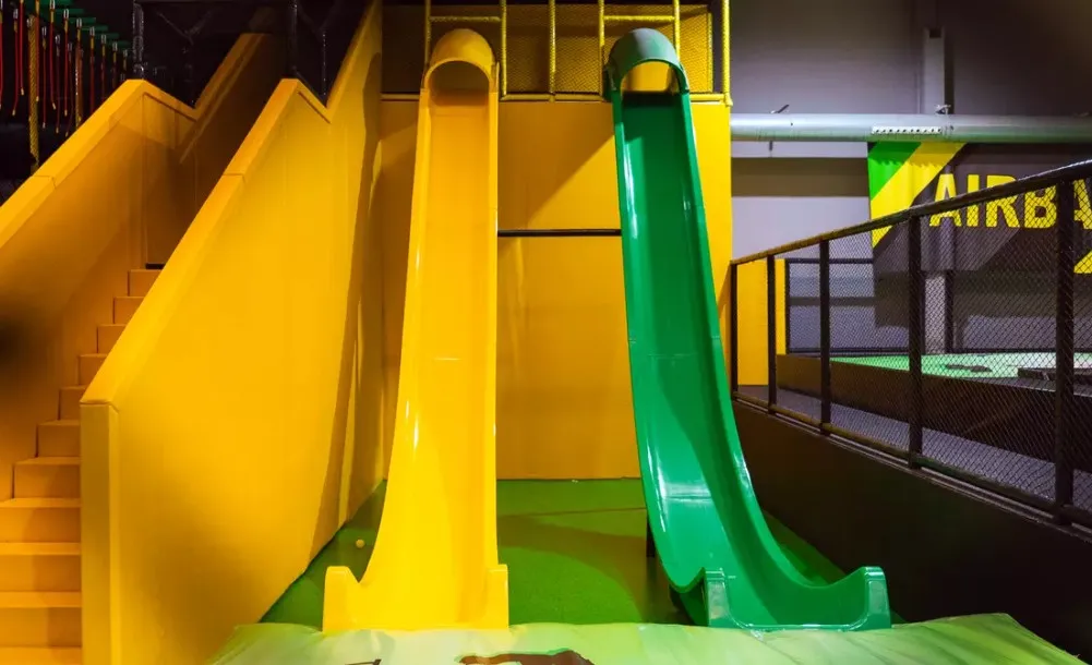Imagen que muestra una de las partes del parque Fun Jump en Valencia con dos toboganes, uno amarillo y uno verde