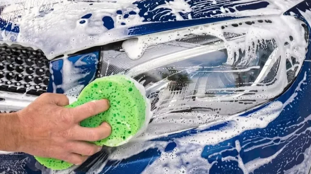 Imagen del detalle de pulido de los faros del coche y el lavado del exterior con jabón especial y productos para no arañar la carrocería